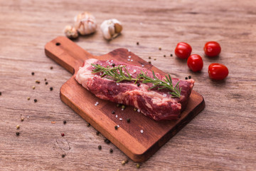 Fresh raw meat for steak on wooden cutting board.
