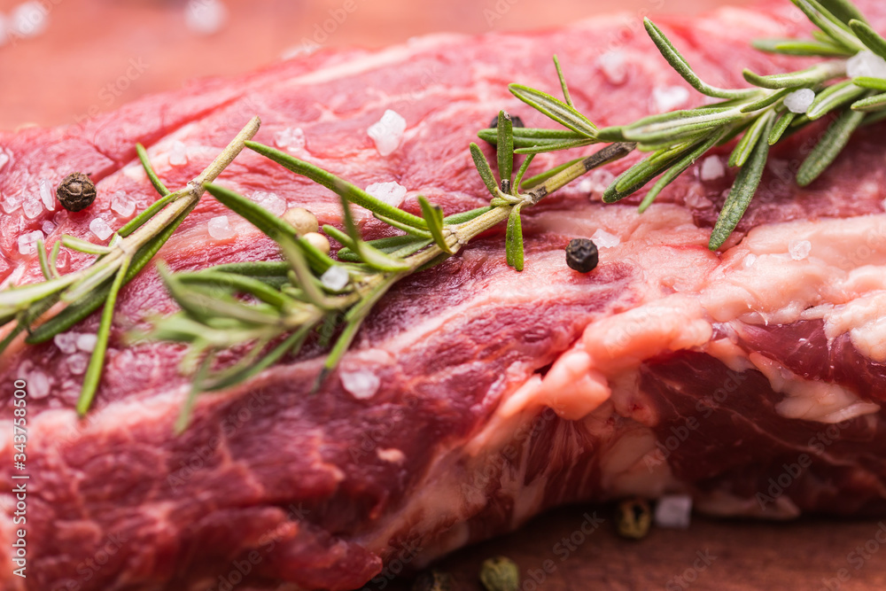 Wall mural raw beef fillet steaks with herbs and spices on wooden background, close-up.