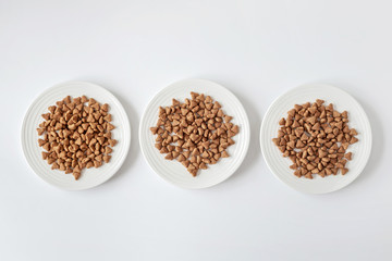 Domestic cat food. Minimalism top view flat lay plate with white dry food. Pet care.