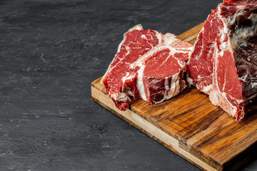 Raw T-bone steak cooking on stone table.