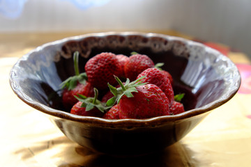 Berries of homegrown strawberries in a ceramic bowl.