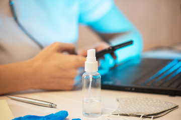 Coronavirus concept. Woman in quarantine for coronavirus covid-19 working from home. Protective mask and sanitizer spray on the working place