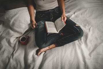 Woman reading book at home on bed.