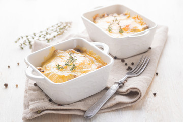 Traditional cheese casserole with chicken and mushrooms and herbs in a serving plate.