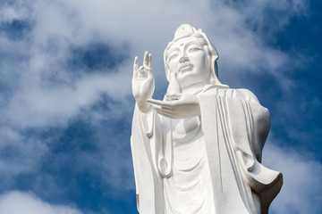 Big white statue of buddha with blue sky and white clouds