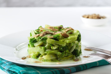 Boiled broccoli with pumpkin seeds on a white plate on the table