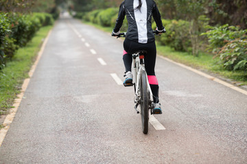 Fototapeta na wymiar Woman cyclist riding a bike on sunny park trail in spring