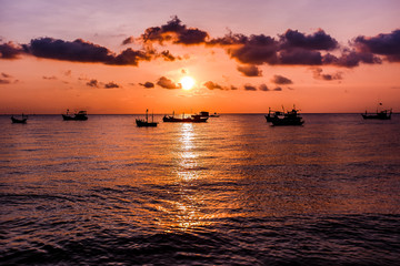 Fototapeta na wymiar Sunset on the beach. Ships and clouds with orange light