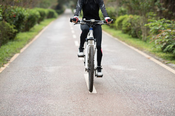 Naklejka premium Woman cyclist riding a bike on sunny park trail in spring