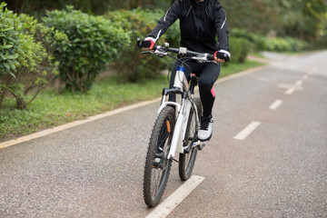 Woman cyclist riding a bike on sunny park trail in spring