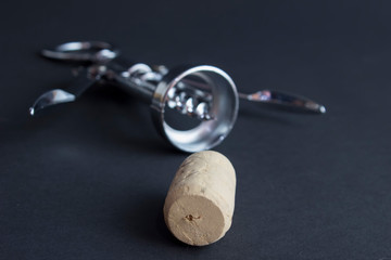 Wine corkscrew with corks on a black background from above