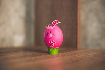 Easter egg in the form of a pink rabbit on a wooden table