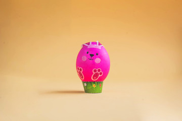 Easter egg in the form of a pink rabbit on an orange background