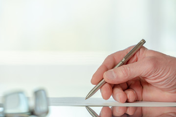 Man signs a document form with a ballpoint pen in the office
