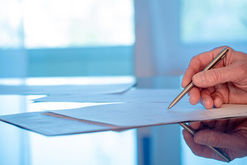 Man signs a document form with a ballpoint pen in the office