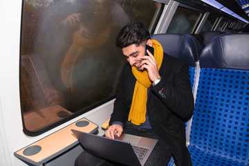 Businessman calls on phone and works on laptop