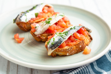 Toasts of marinated anchovies with fresh tomato and olive oil