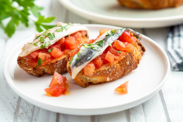 Toasts of marinated anchovies with fresh tomato and olive oil