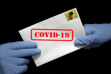 Ludzkie ręce w rękawicach ochronnych z listem, który może zawierać wirusa COVID-19. Przesyłki pocztowe mogą rozprzestrzeniać koronawirusa.

 - obrazy, fototapety, plakaty