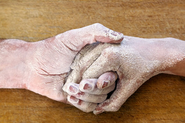 Male and female baker hands covered in flour on the table