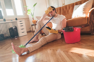 Handsome man cleaning his house with mop and plastic bucket, he working hard