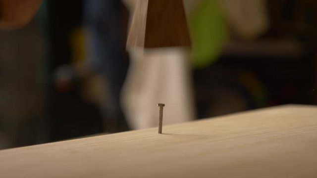 Macro, martillo clavando un clavo en en una tabla en un taller de carpinter&iacute;a artesanal