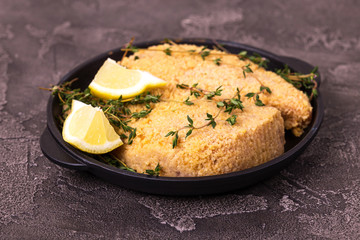 Raw ready to cook chicken breast fillets with breading, lemon, thyme