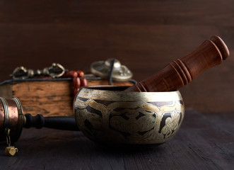 Tibetan singing copper bowl with a wooden clapper on a brown wooden table