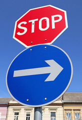 Stop sign and arrow sign at the road crossing