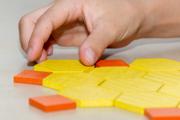 Tangram hexagon flower colored child geometric puzzle piece with childs hands  moving pieces side view.