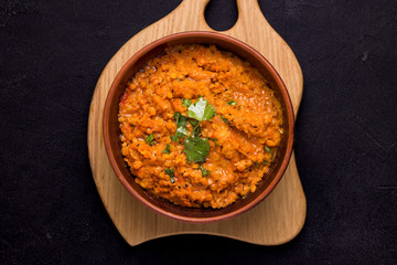 Dhal Indian cream bean soup in a bowl on a wooden plank on a black background. Traditional indian food concept