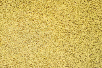 Yellow wall background. Texture beige pebble dash stucco house facade.