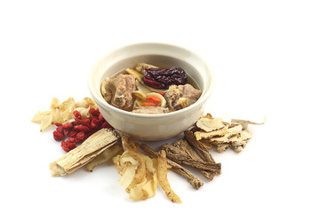 Bowl of clear soup around with  many chinese herbal medicine on white background