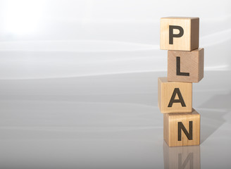 PLAN word on a wooden cubes on white grey glossy background with reflection
