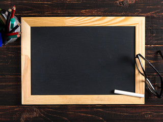 Chalk black board, glasses and chalk on a wooden table, copy space.