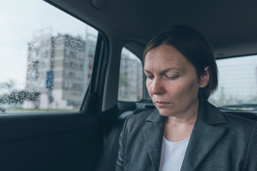 Worried businesswoman sitting at car back seat