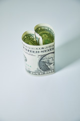 Heart folded from one dollar bill over gray background with copy space. Concept image of money love