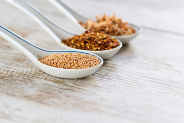 Spices and herbs in porcelain spoons over a wooden background