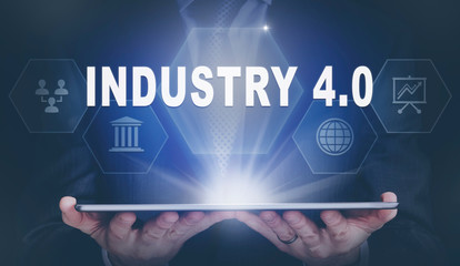 Businessman holding a computer tablet display projecting a Industry 4.0 concept.