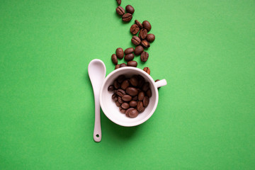 white cup and spoon on a green background, coffee grains. Good morning concept