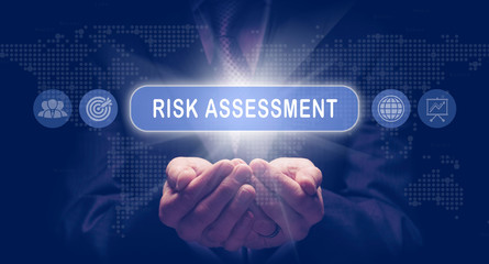 Businessmans cupped hands holding an Risk Assessment business concept on a computerised display.