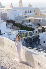 Fototapeta na wymiar Beautiful bride In a white dress posing against the backdrop of the city of Thira, Santorini.