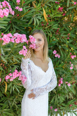 Portrait of a beautiful bride in a white dress in a bush of flowers.