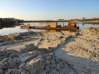 excavation machine at earthmoving work in sand quarry. Extraction of sand from a lake.