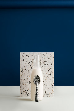 Milk bottle and spoon with tile on table