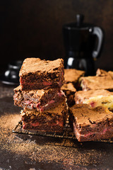 Brownie cheesecake cake with cherry and chocolate on a dark background. Selective focus.