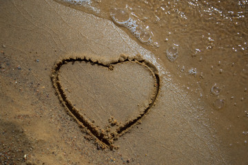 Obraz na płótnie Canvas drawing hearts in the sand