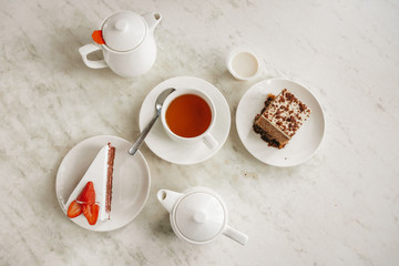 Tea party with sweet desserts. Ceylon black tea with strawberry cheesecake. A metal teapot with pink tea in a restaurant. Hot drink on cafe table. Tea ceremony
