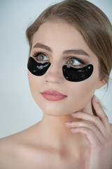 Under Eye Skin Black Patch. Closeup Of Beautiful Young Woman Face With Moisturizing Collagen Mask Pad On Healthy Fresh Facial Skin On White Background