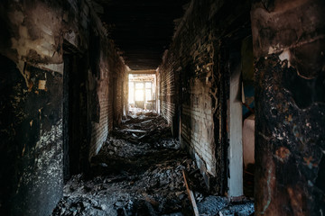 Fototapeta na wymiar Burnt old house interior. Ruined coridor walls in black soot. Consequences of fire
